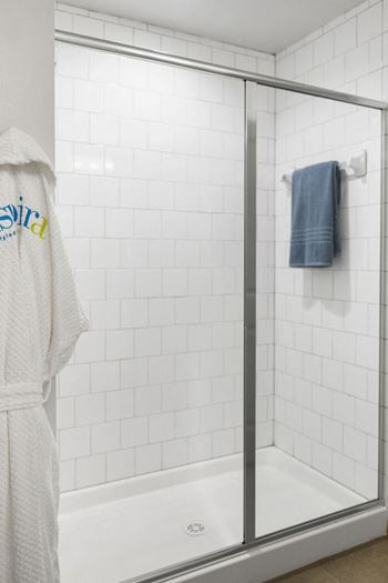A white bathroom with a shower and a towel hanging on the side of the shower